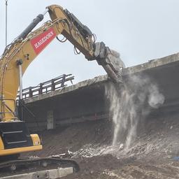 Ein Bagger reißt eine Brücke ab.