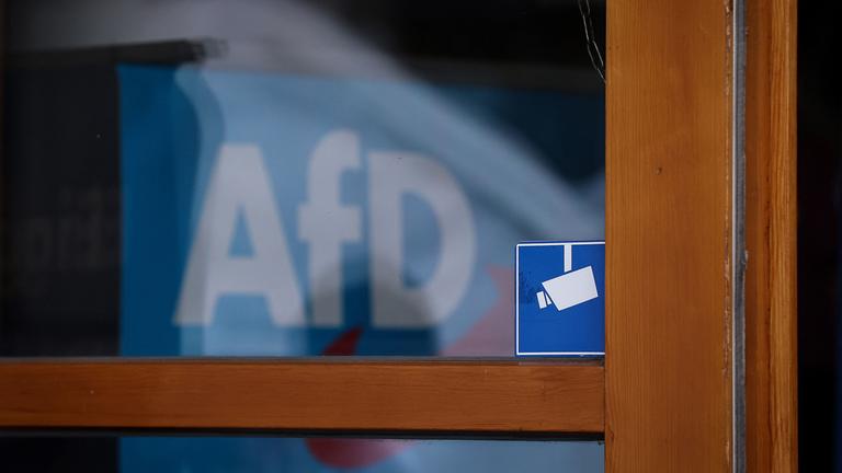 Das Logo der AfD ist hinter einem Fenster zu sehen.
