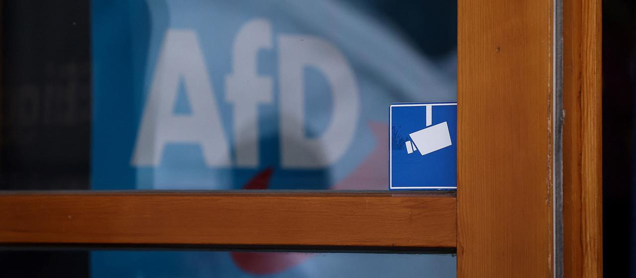 Das Logo der AfD ist hinter einem Fenster zu sehen.
