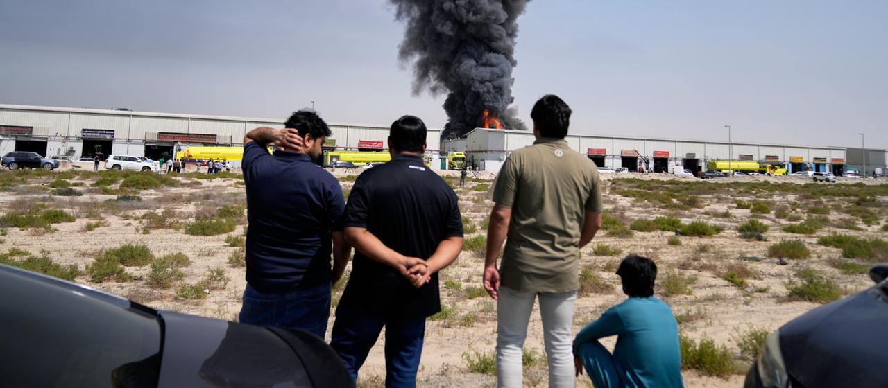 Anwohner beobachten, wie Flammen und eine schwarze Rauchwolke aus einem Lagerhaus im Industriegebiet von Sharjah City in den Vereinigten Arabischen Emiraten aufsteigen,