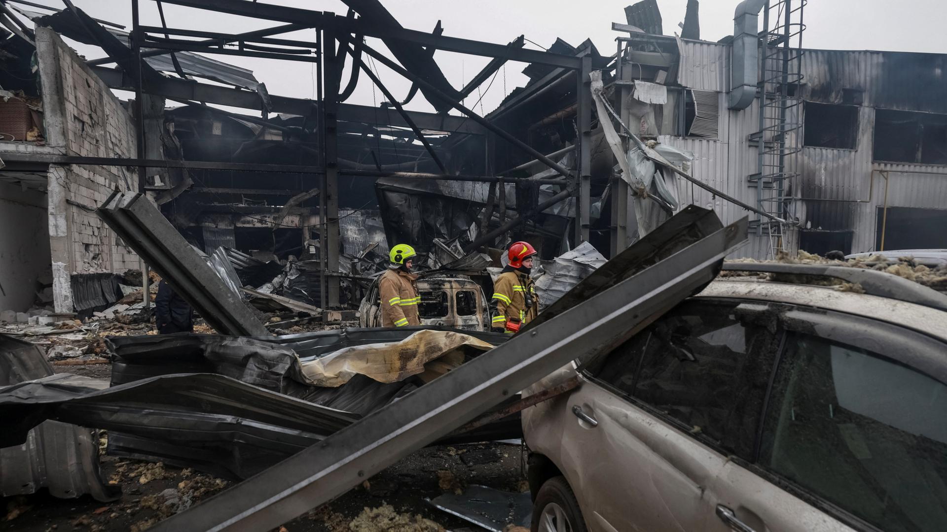 RettungskrÃ¤fte stehen vor TrÃ¼mmern eines GebÃ¤udes nach einem Drohnenangriff. | REUTERS