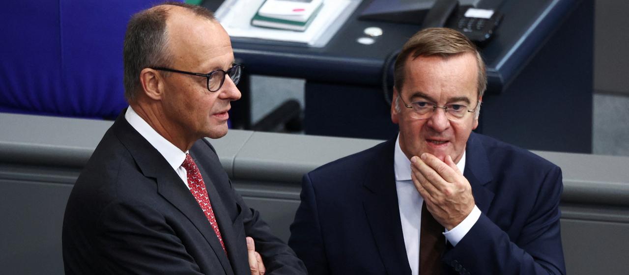 Friedrich Merz und Boris Pistorius stehen nebeneinander im Bundestag. | REUTERS Friedrich Merz und Boris Pistorius stehen nebeneinander im Bundestag.