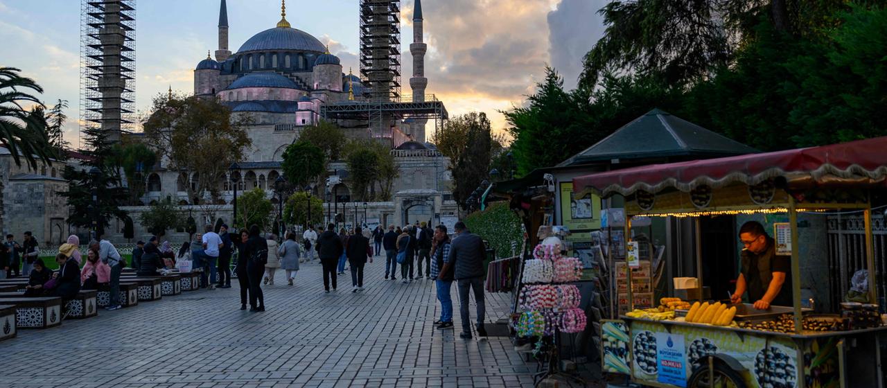 Menschen laufen einem Gehweg vor einer Moschee in Istanbul