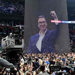 Unterstützer von Serbiens Präsidenten Vucic versammeln sich vor einem großen Plakat mit dem Konterfei des Präsidenten in Belgrad.