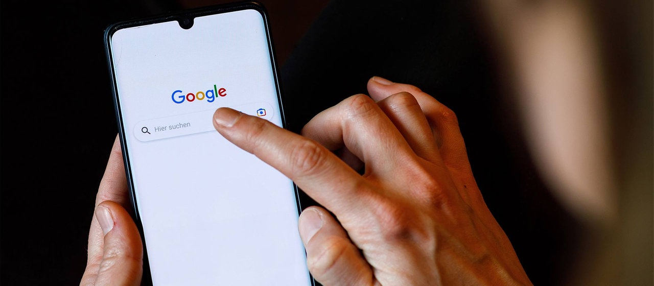 Ein Finger tippt auf das Feld der Google-Suche auf einem Smartphone.