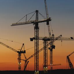 Kräne einer Großbaustelle im Abendlicht.
