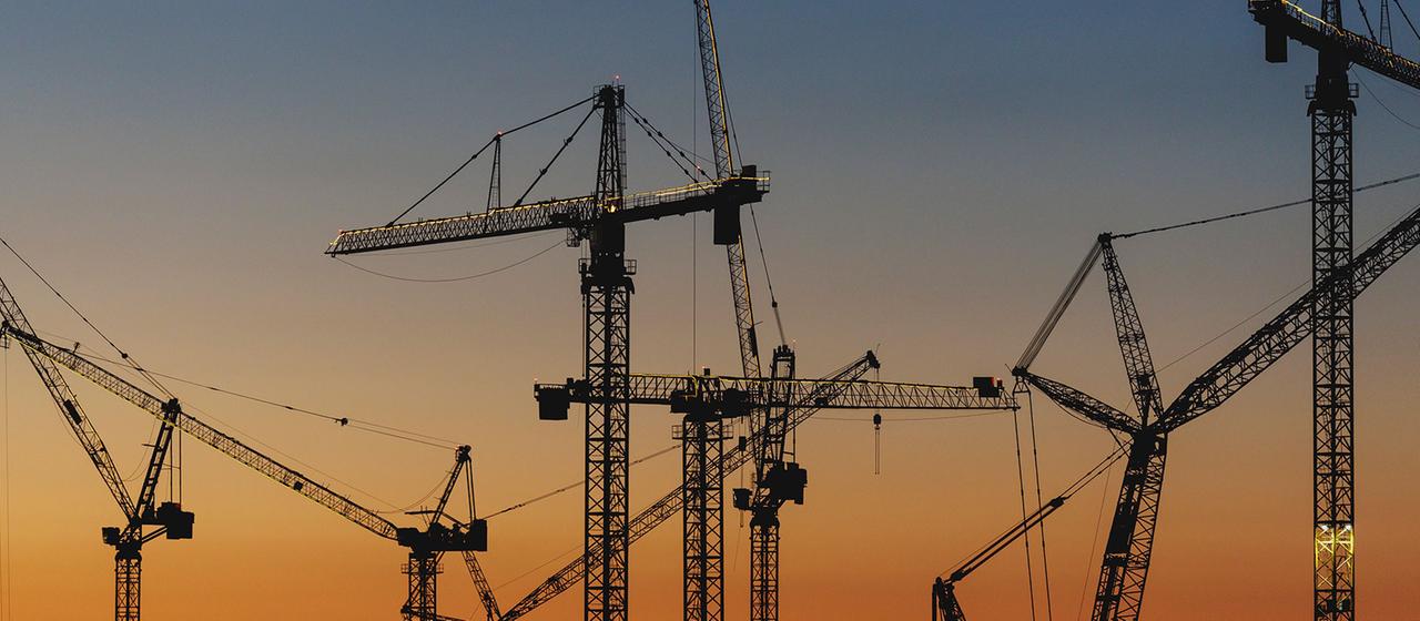 Kräne einer Großbaustelle im Abendlicht.