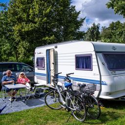 Urlauber sitzen vor ihrem Caravan auf einem Campingplatz am Schweriner See.