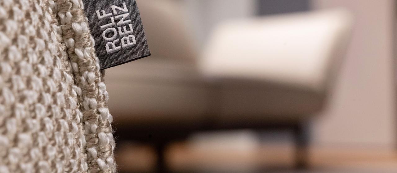 Sitzgruppe mit Logo von Hersteller Rolf Benz an der Wand