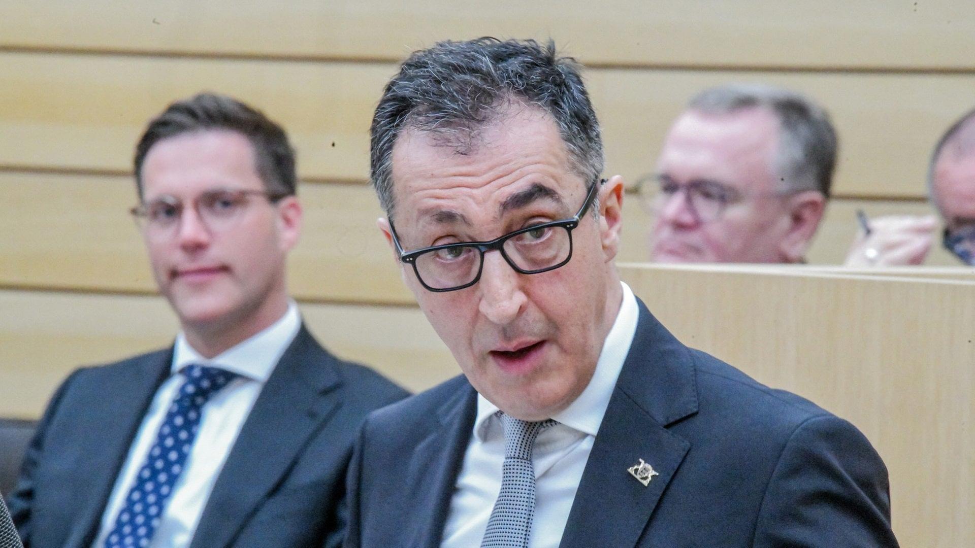 Ministerpräsident Cem Özdemir (Grüne) spricht im Landtag. Dahinter ist Innenminister Manuel Hagel (CDU) zu sehen. Die Diskussion um den Opernneubau in Stuttgart, bei dem sich Özdemir beteiligt hat, zeigt, wie die unterschiedlichen Ansätze der Regierungsparteien liegen. | dpa Bildfunk, picture alliance/dpa | Jason Tschepljakow