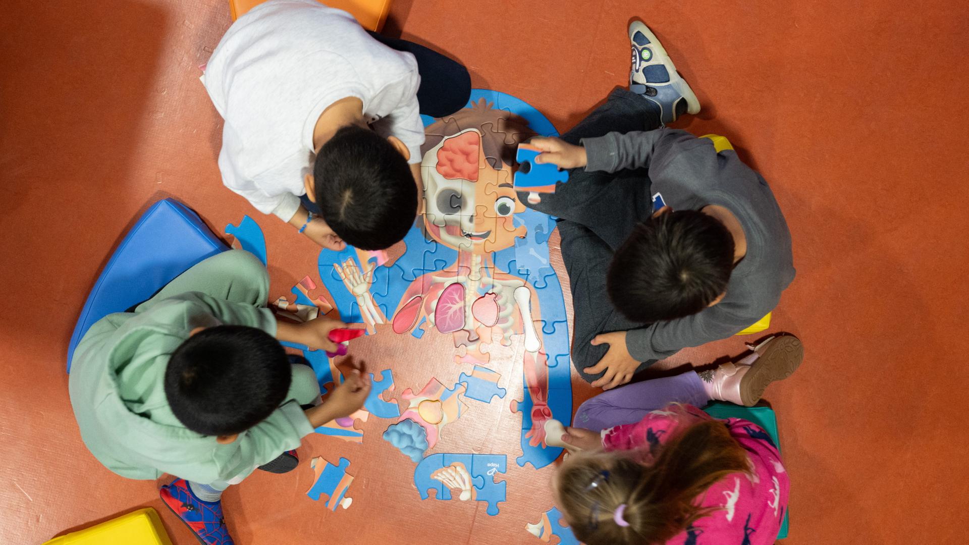 Kinder legen in einer Kindertagesstätte ein Puzzle zusammen. | dpa
