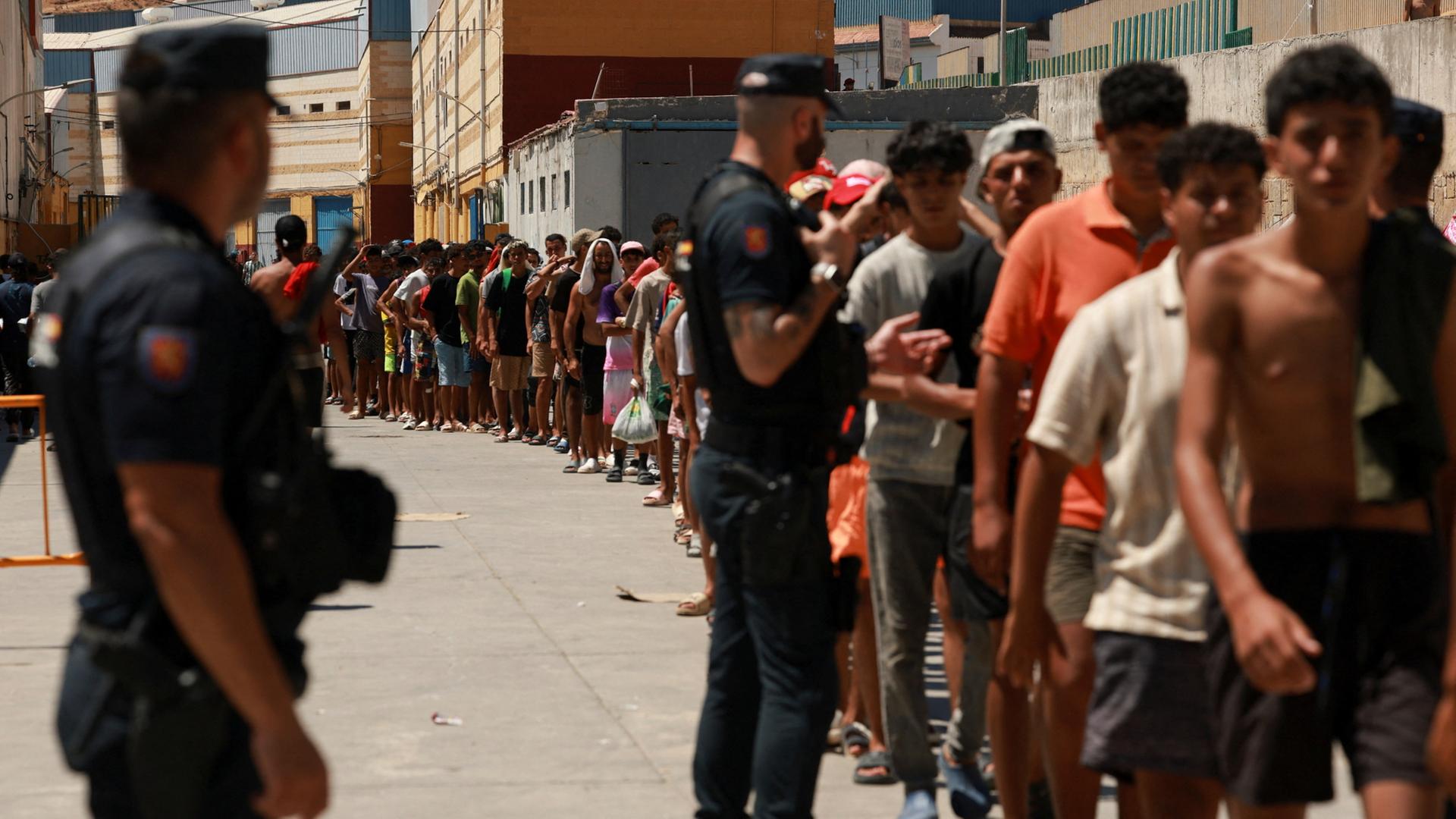 Migranten stehen im spanischen Ceuta Schlange, um Grundnahrungsmittel zu erhalten. | REUTERS