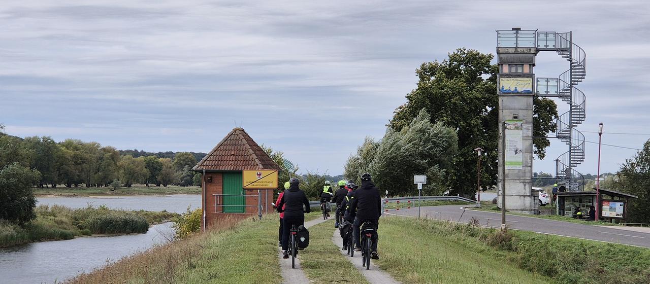 Fahrradfahrer fahren am Grenzturm Lenzen vorbei.