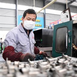 Ein Mann mit Atemschutzmaske arbeitet an einer Produktionslinie für Autozubehör in einer Werkstatt im Bezirk Qijiang.