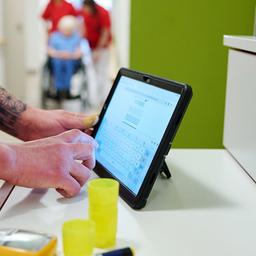Eine Pflegekraft dokumentiert ihre Arbeit auf einem Tablet-Computer