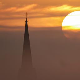 Sonnenaufgangn im Nebel, im Vordergrund ein Kirchturm
