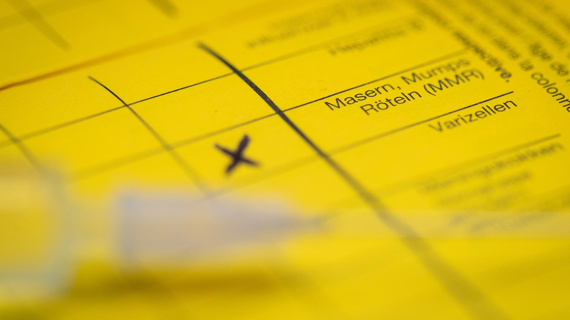 Eine Spritze liegt auf einem Impfpass. | dpa