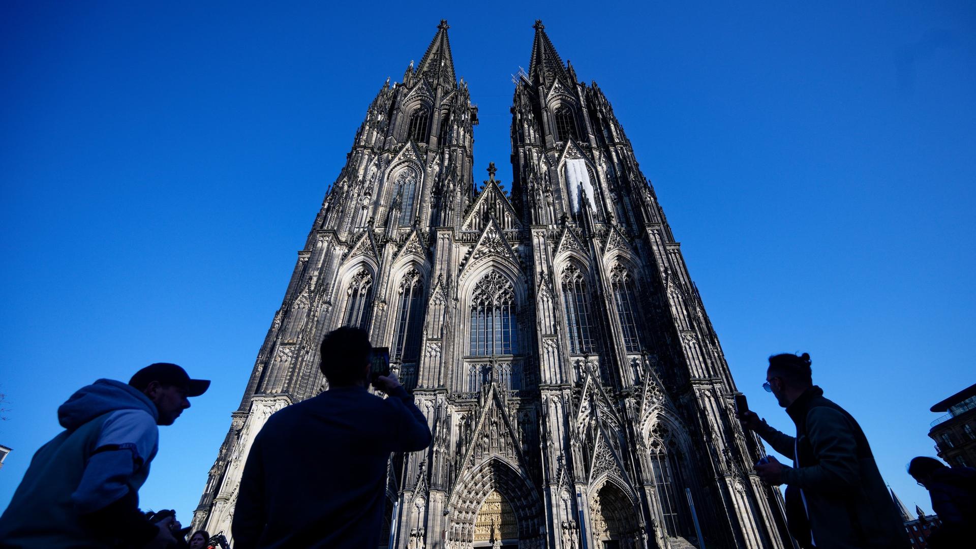 Der Kölner Dom vor blauem Himmel mit Besuchern davor | dpa / Kaiser
