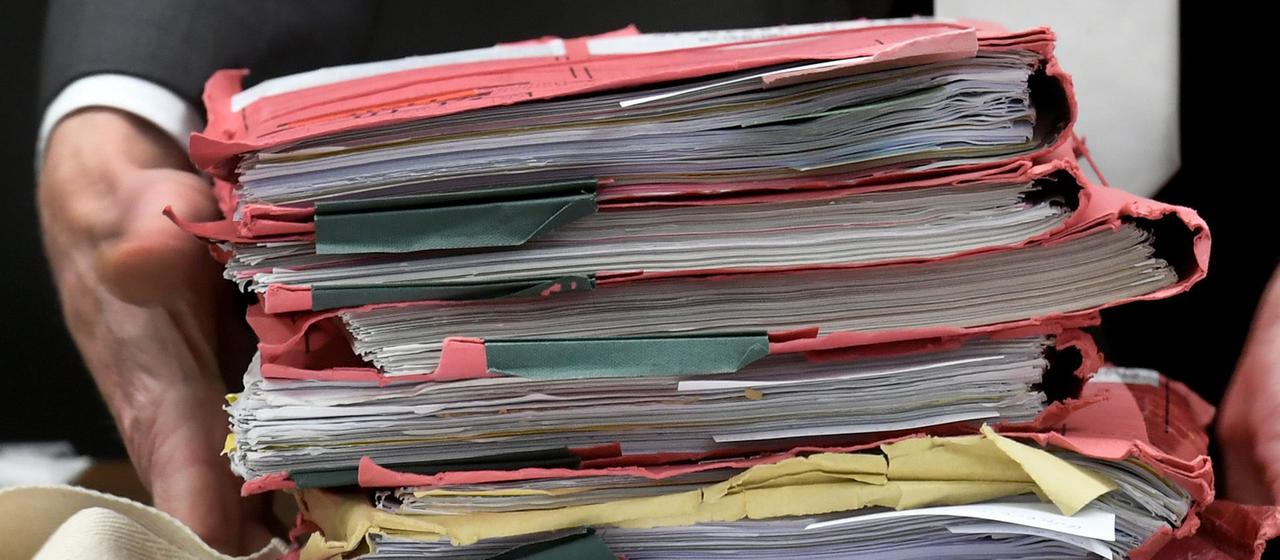 Akten werden auf einen Tisch gelegt.