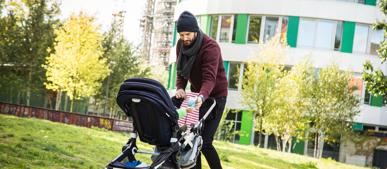 Ein Mann schiebt einen Kinderwagen