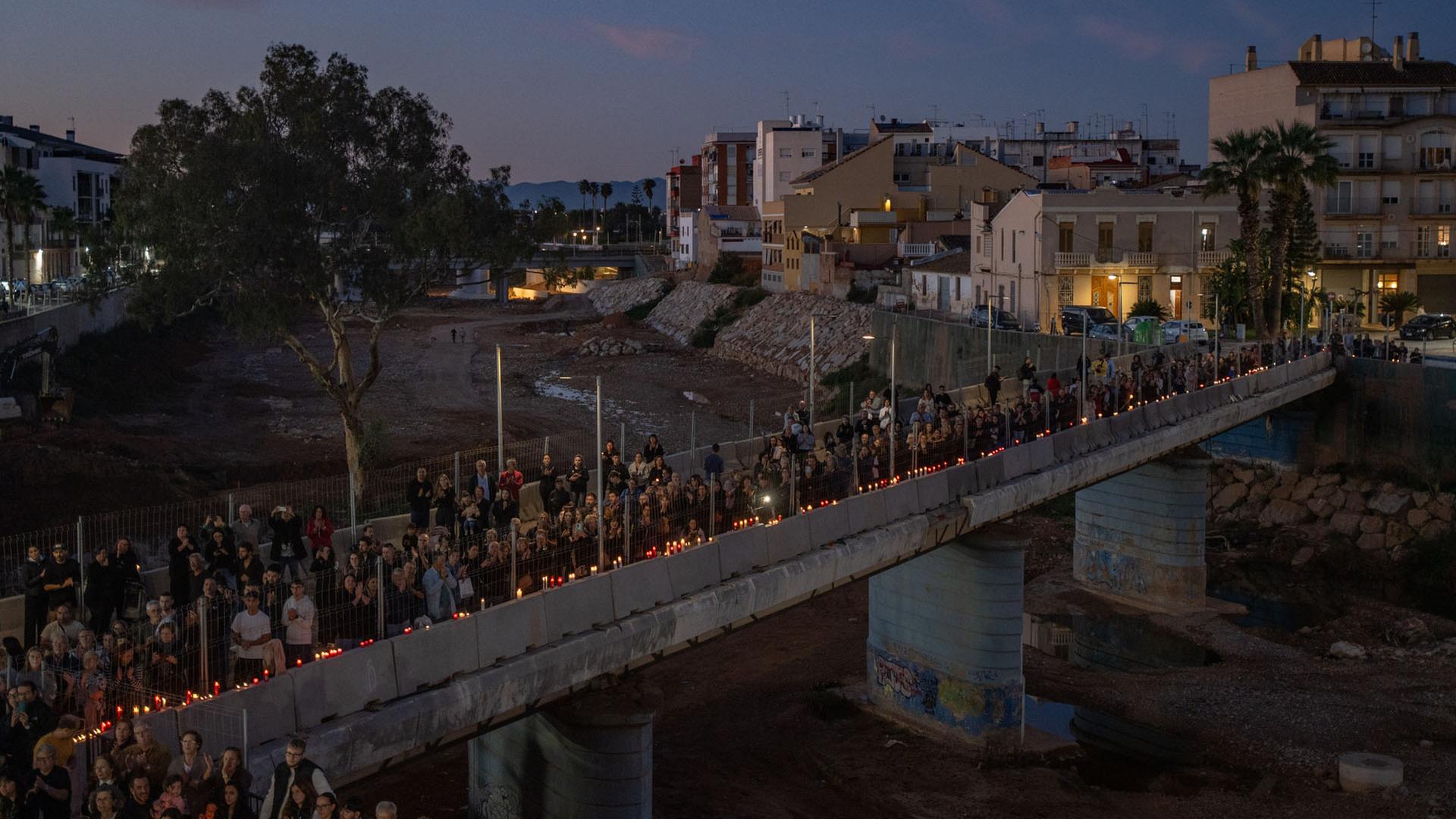 Mit Kerzen in HĂ€nden bilden Teilnehmer einer Gedenkveranstaltung eine Menschenkette in Paiporta, Spanien. | dpa