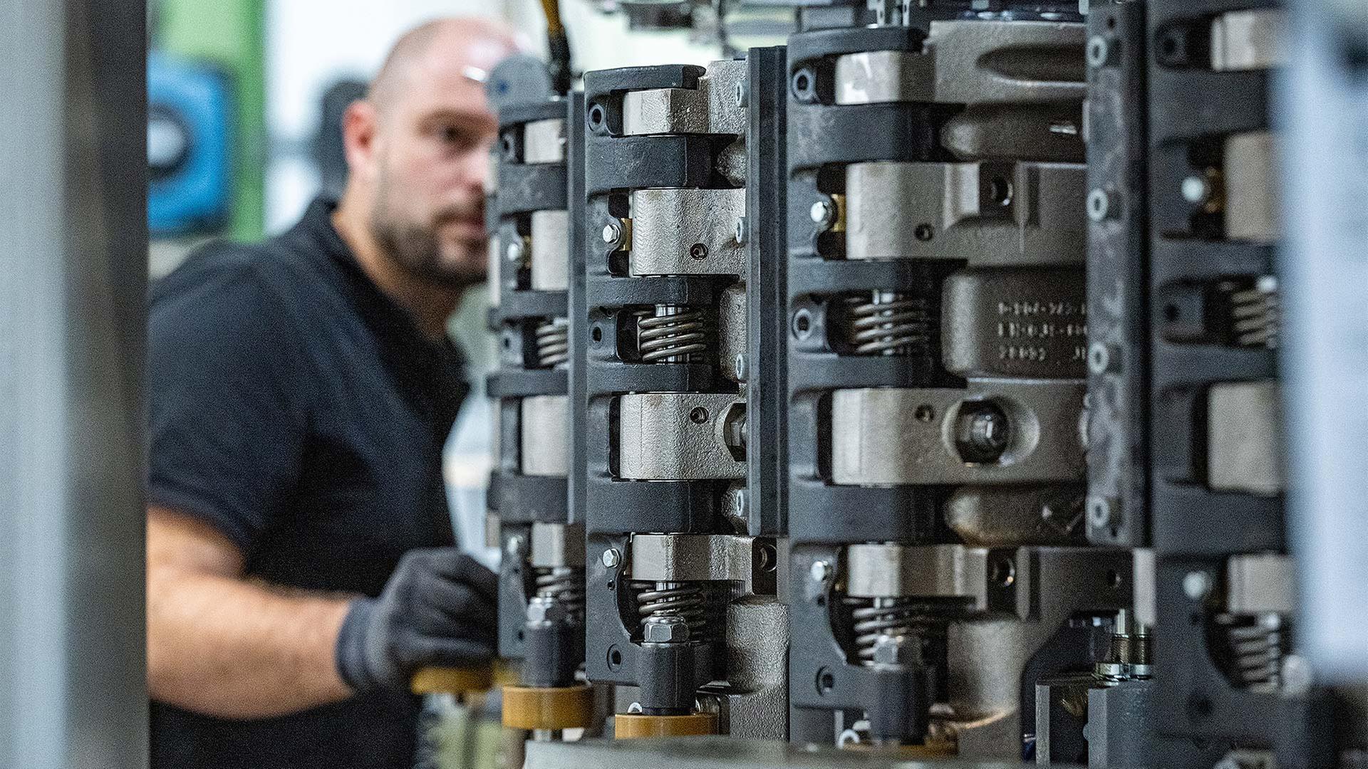 Ein Krones-Mitarbeiter arbeitet in der Produktion an einer Streckblasmaschine. | picture alliance/dpa