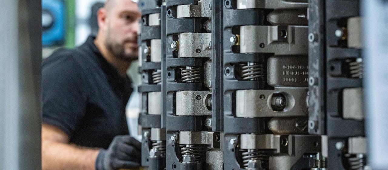 Ein Krones-Mitarbeiter arbeitet in der Produktion an einer Streckblasmaschine.