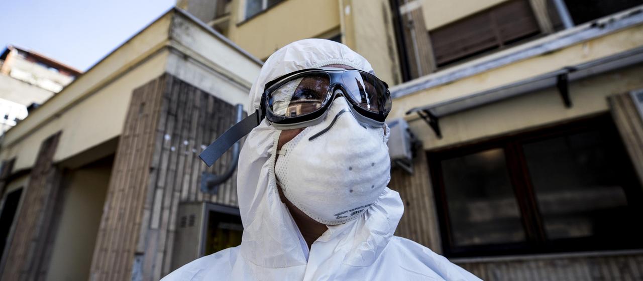 Ein Sanitäter in Rom trägt eine komplette Schutzausrüstung aus Brille, Anzug und Atemmaske gegen das Coronavirus.