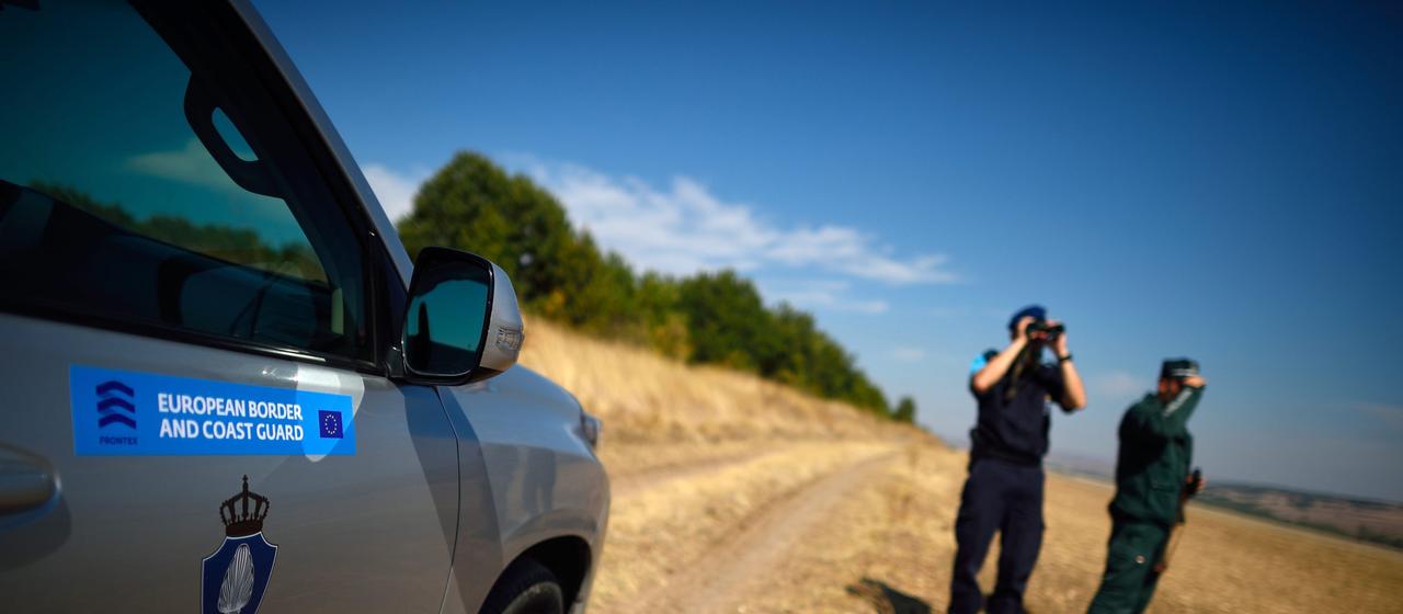 Frontex-Mitarbeiter stehen neben einem Auto der Agentur
