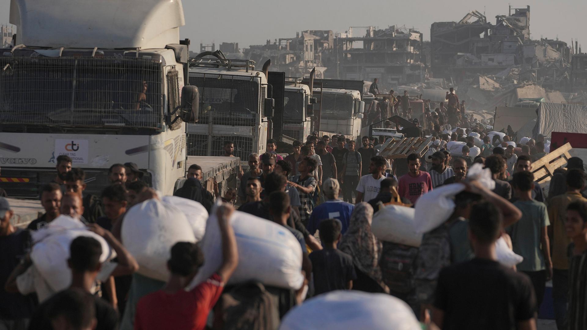 Palästinenser tragen Mehlsäcke, die von einem humanitären Hilfskonvoi abgeladen wurden, der Gaza-Stadt aus dem nördlichen Gazastreifen erreicht hat | AP