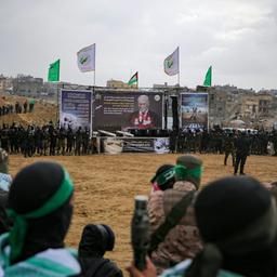 Hamas-Terroristen bei der Übergabe getöteter Geiseln vor einem Plakat, auf dem der israelische Premierminister Benjamin Netanjahu als Vampir abgebildet ist