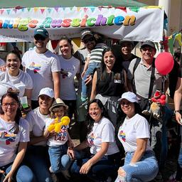 Menschen unterschiedlicher Nationalität stehen vor einem Gebäude
