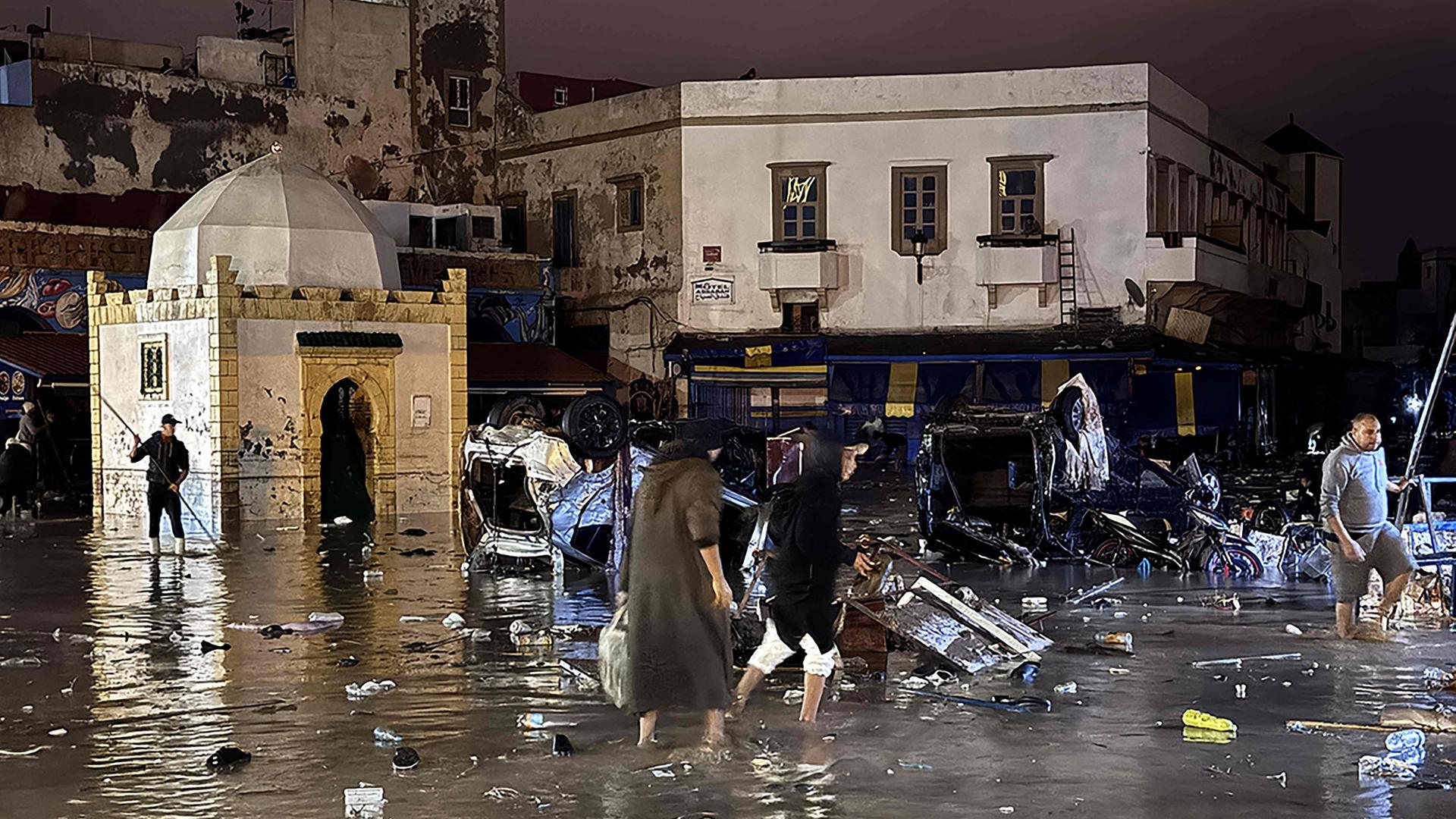 Menschen waten nach einer Sturzflut durch das Wasser im marokkanischen Safi | AFP