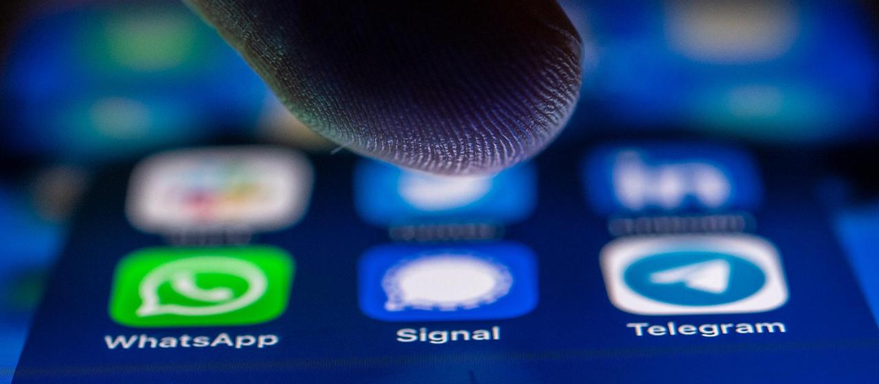 Close-up with finger over the messaging apps WhatsApp, Signal and Telegram on a smartphone