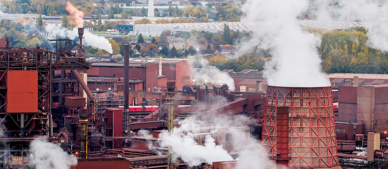 Qualm und Gasflammen über dem Werksgelände einer Stahlhütte.