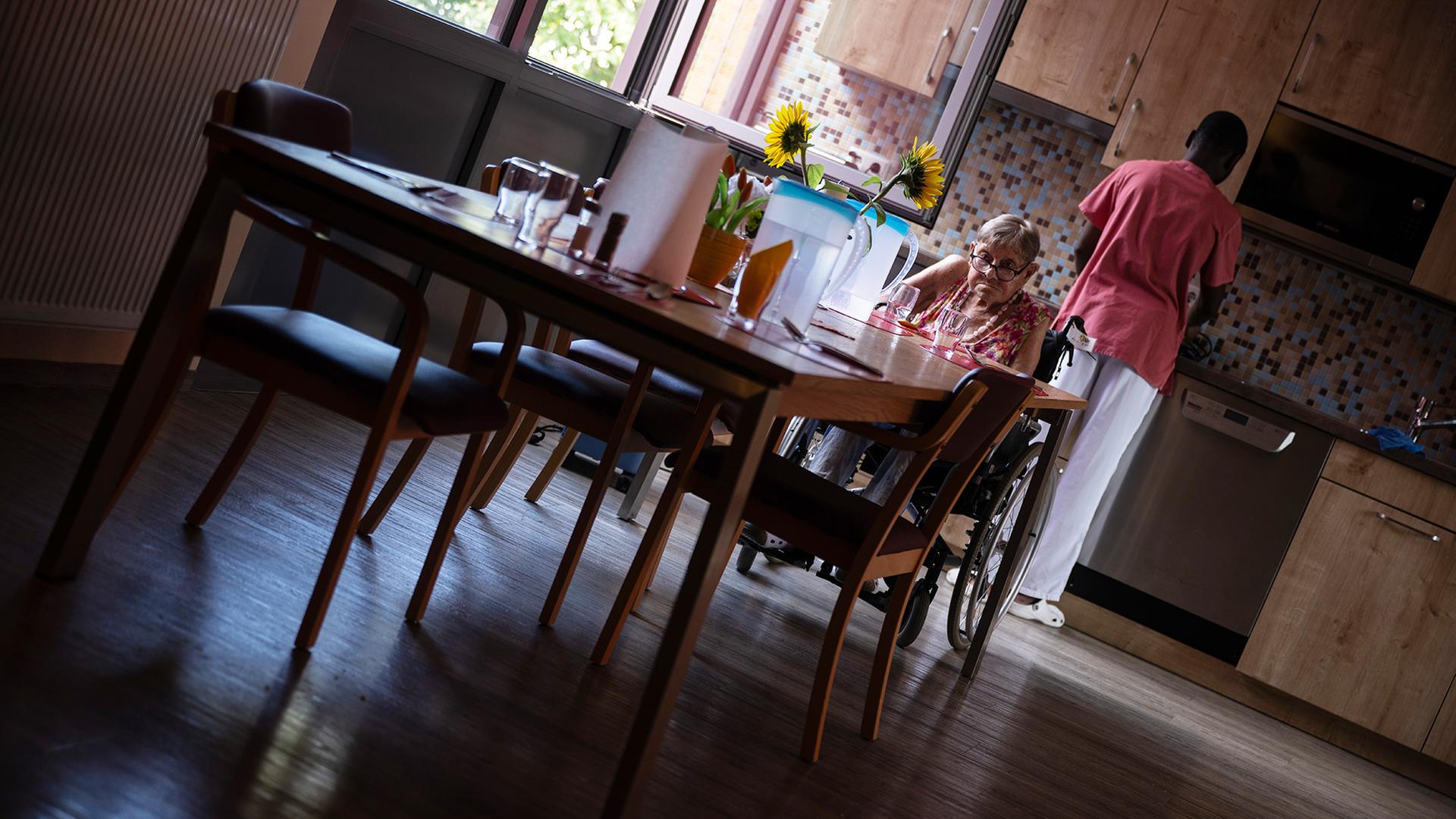 Eine Bewohnerin sitzt in einer Pflegeeinrichtung an einem Tisch. | picture alliance/dpa