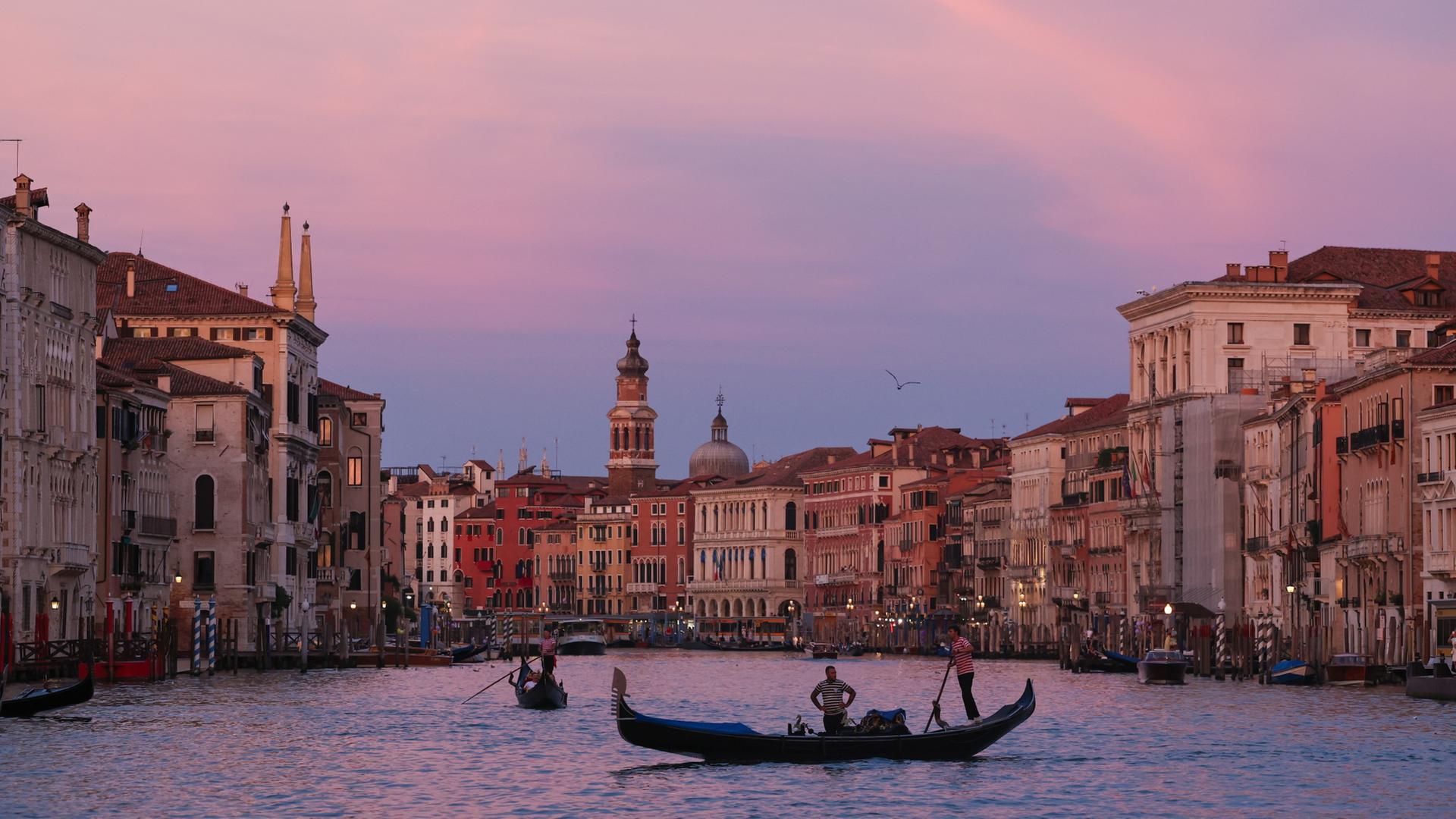 Menschen rudern Gondeln bei Sonnenuntergang in Venedig. | Li Jing/XinHua/dpa