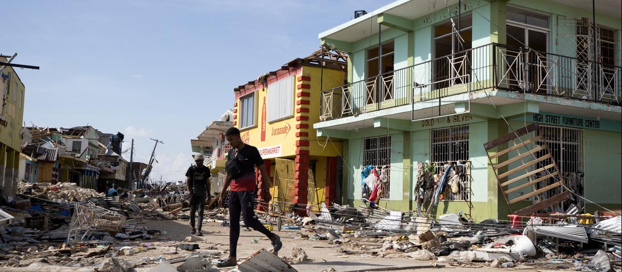 Menschen gehen in Black River, Jamaika, an Gebäuden vorbei, die durch den Hurrikan Menschen gehen in Black River, Jamaika, an Gebäuden vorbei, die durch den Hurrikan