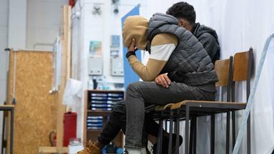 Zwei junge Männer sitzen in einer Polizeiinspektion.