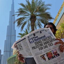 In Mann liest in Dubai eine Zeitung mit der Schlagzeile "Israel stoppt die Annexion zur Aufnahme diplomatischer Beziehungen zu den Vereinigten Arabischen Emiraten".