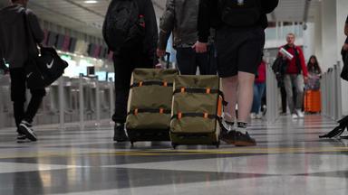 Reisende schieben ihre Koffer durch den Flughafen München