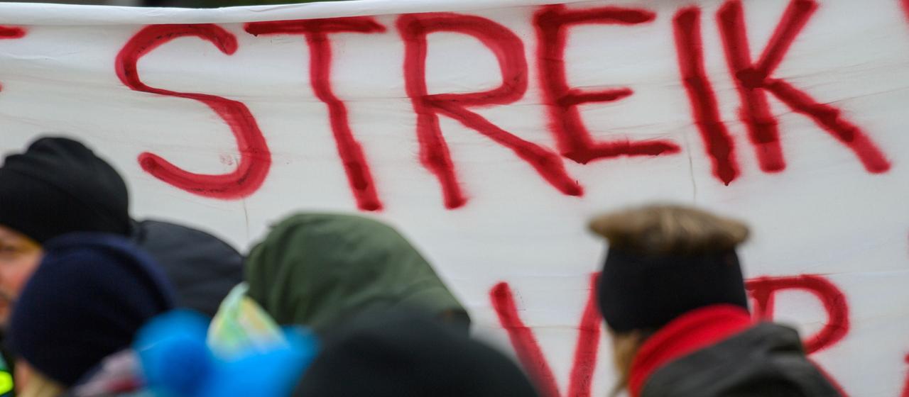 Streikende Menschen mit Plakaten