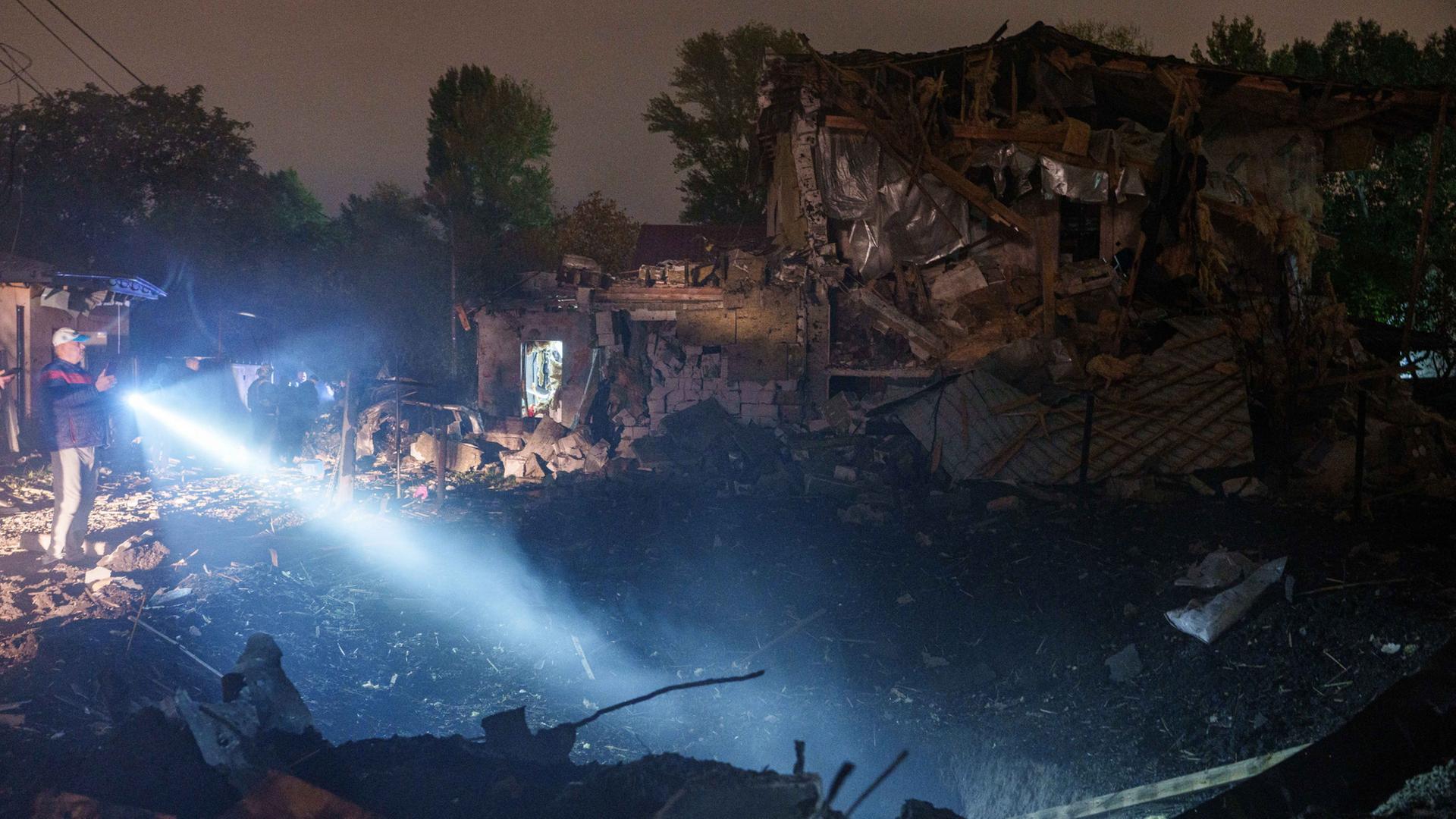 Ein Mann scheint mit einer Taschenlampe auf ein Haus in Kiew, das von einer Drohne zerstört wurde. | AP Photo/Evgeniy Maloletka