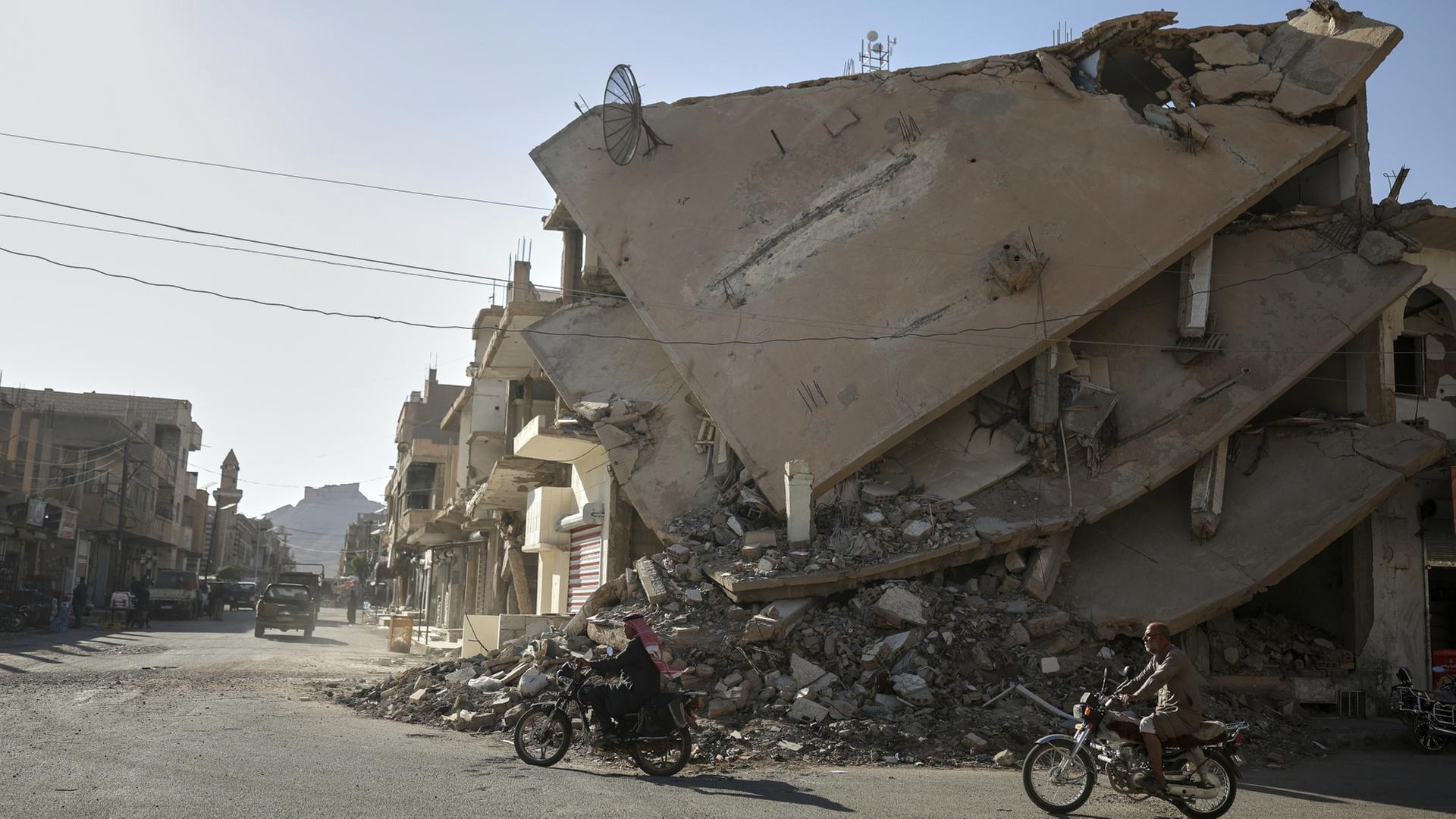  Anwohner fahren auf einem Motorrad durch eine vom Krieg zerstörte Straße der Oasenstadt Palmyra | dpa