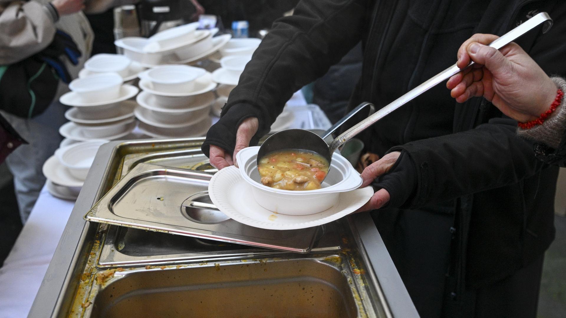 Eine Helferin gibt für wohnungslose Menschen heiße Suppe aus. | dpa