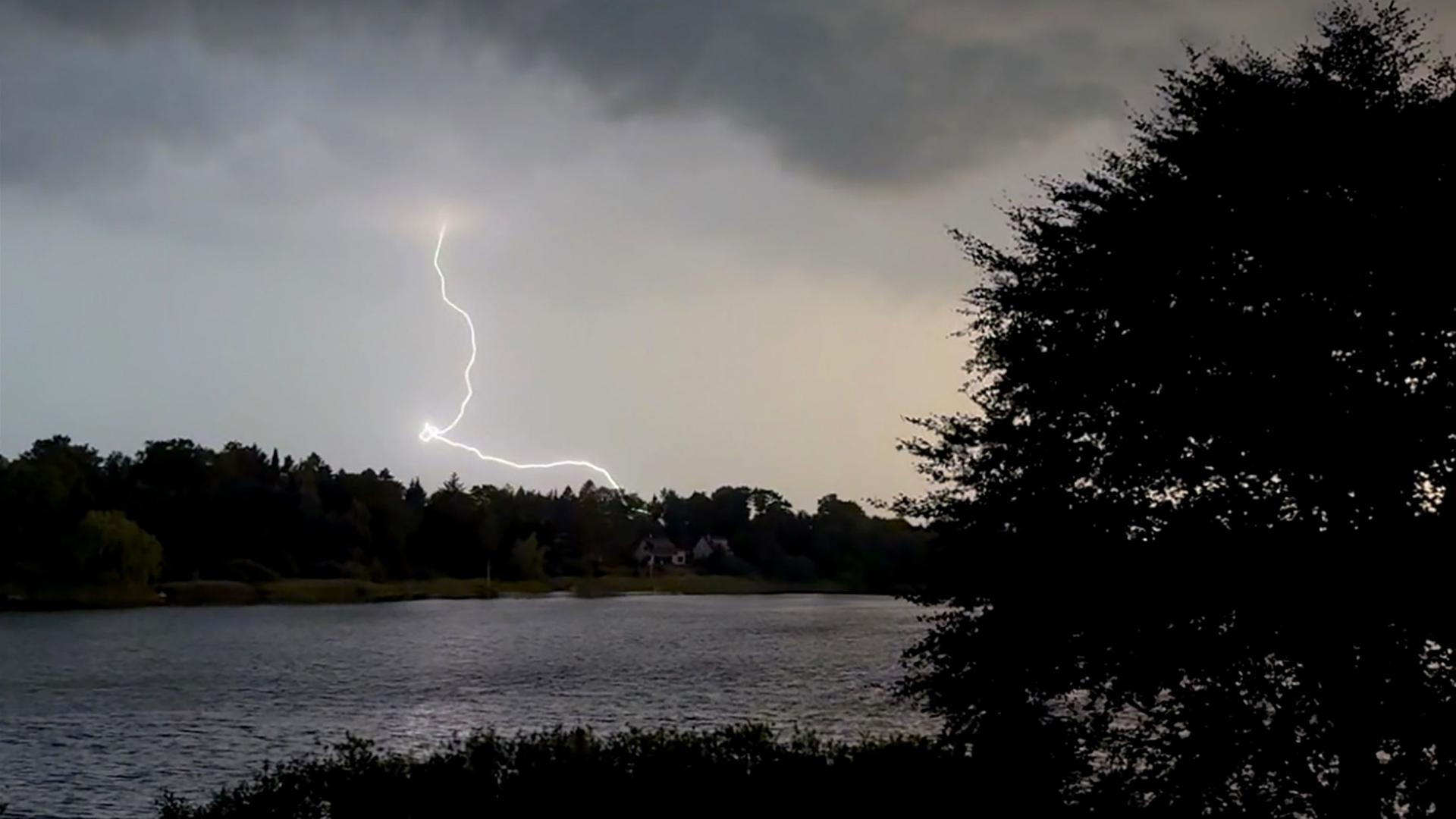 Ein Blitz am grauen Gewitterhimmel �ber einem See | Daniel Bockwoldt/dpa