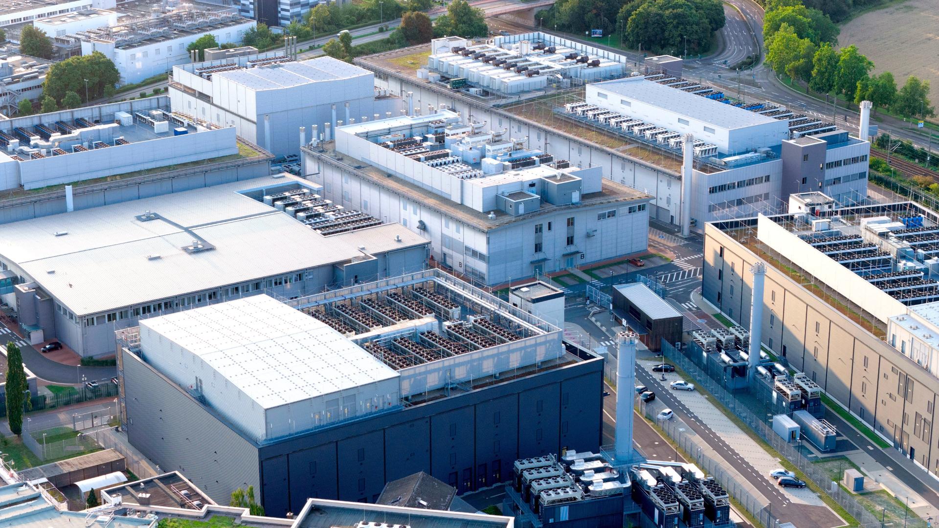Blick auf mehrere graue Gebäudehallen mit erkennbaren Lüftungsanlagen und Türmen | picture alliance / Visually | Hugo Kurk
