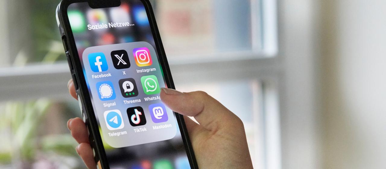 Auf dem Display eines Handys sind unterschiedliche Social-Media-Apps zu sehen.