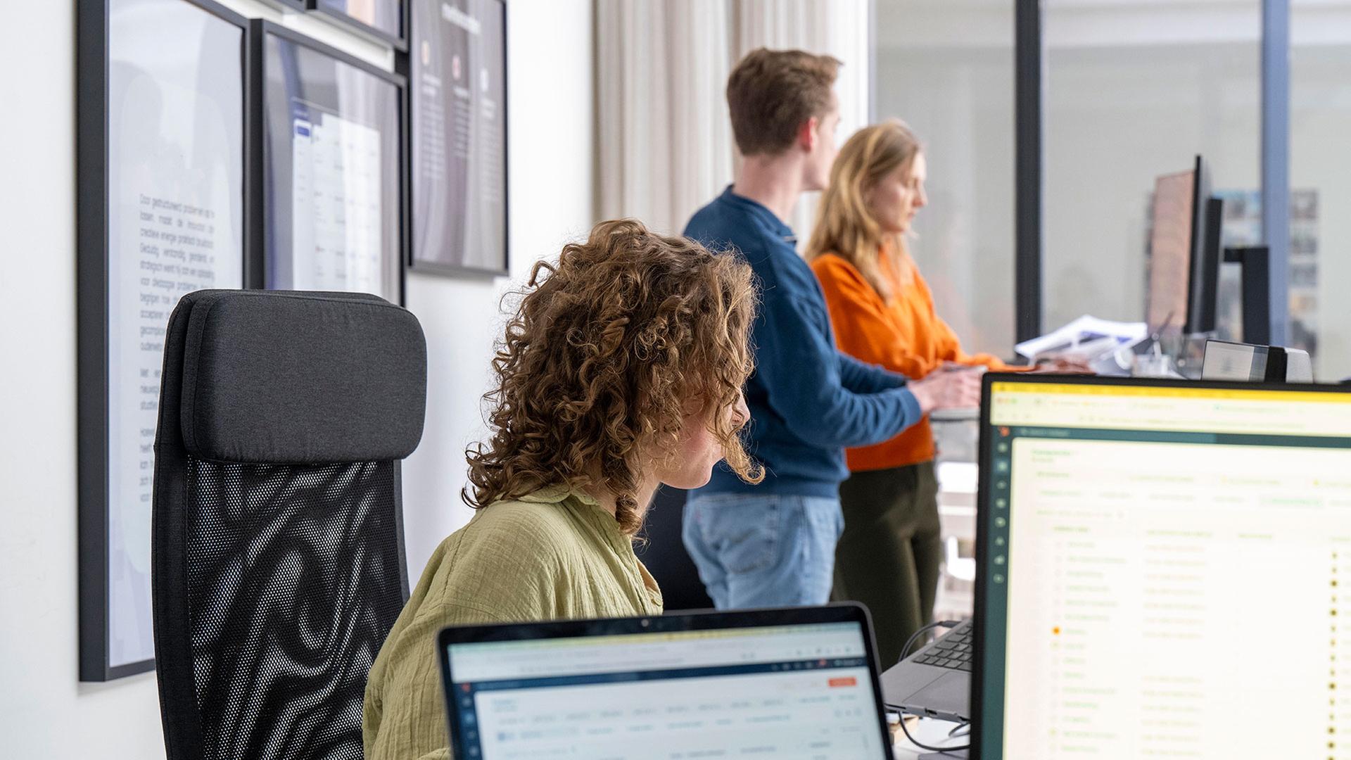 Drei Berufstätige arbeiten in einem modernen Büroraum.  | picture alliance / Image Source