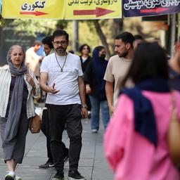 Iraner gehen eine Straße in Teheran entlang.